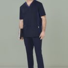 Person in navy blue scrubs holding a notebook, smiling against a light green background.