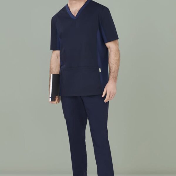 Person in dark scrubs and white shoes holding a notebook, standing against a plain background.