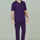 Person in purple medical scrubs with stethoscope, smiling against a gray background.