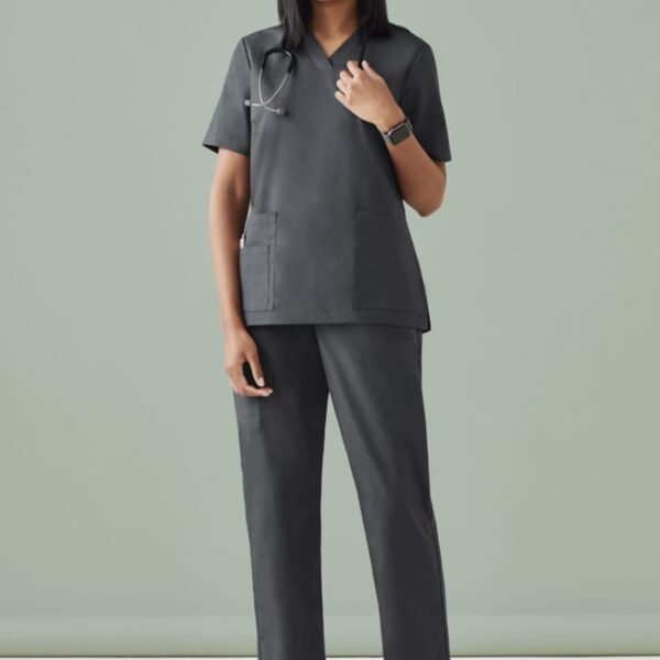 Person in dark scrubs with a stethoscope, standing against a light green background.