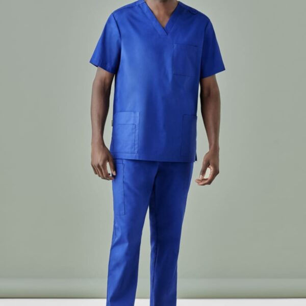 Person in blue scrubs and white shoes against a gray background, smiling.