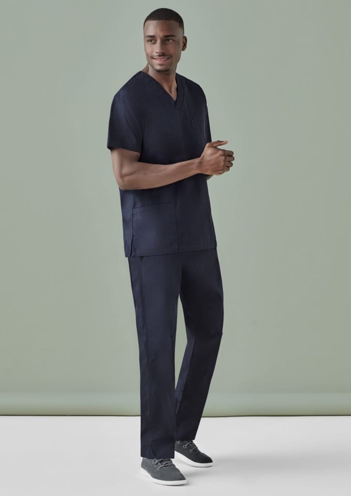 A person in dark medical scrubs stands on a light background.