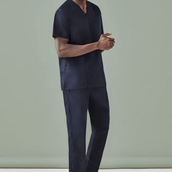 Person wearing a navy scrub outfit stands against a light green background.