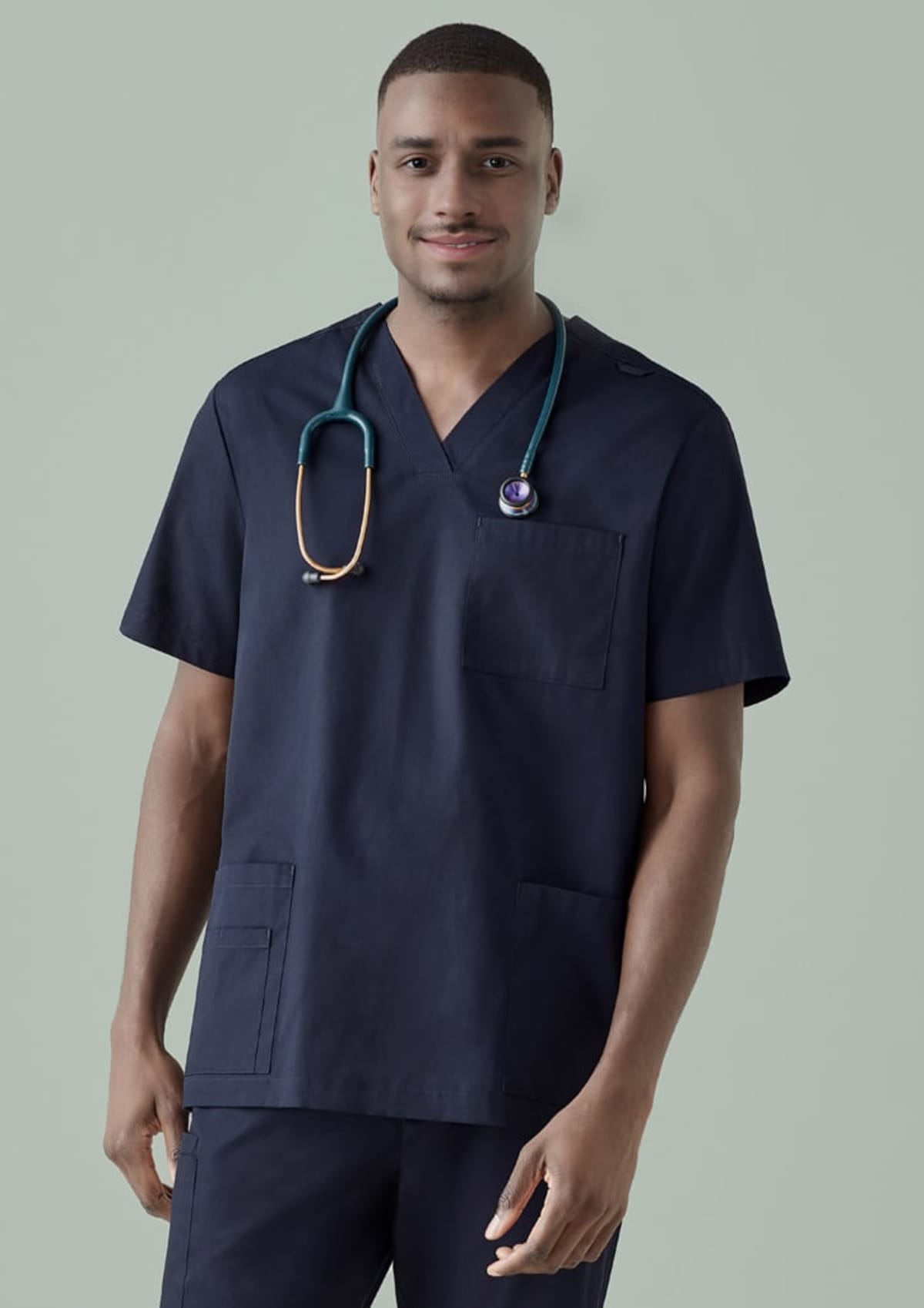 Smiling person in navy scrubs with a stethoscope against a light green background.
