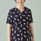 Smiling woman in animal-print scrubs on a light green background.
