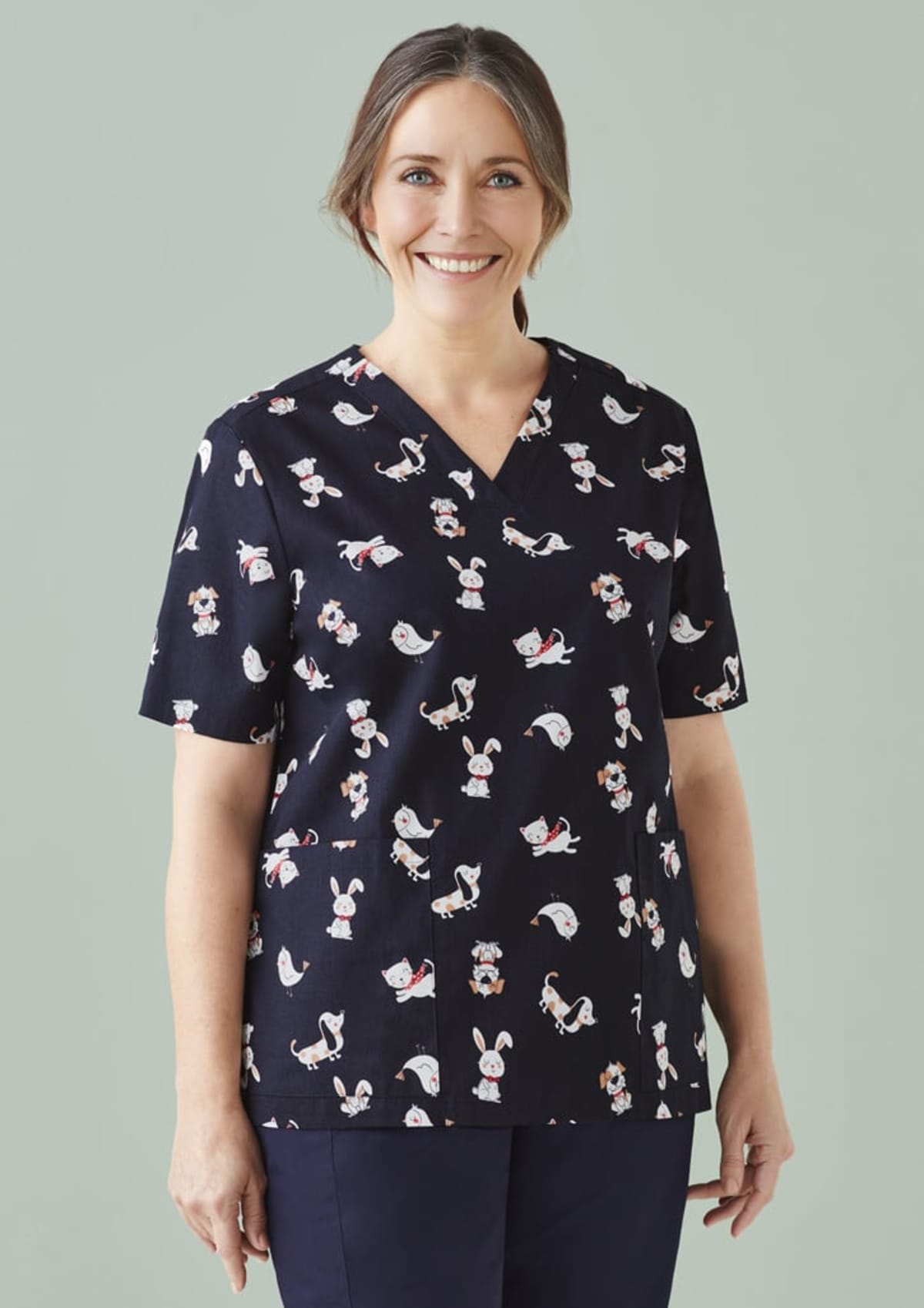 Smiling woman in animal-print scrubs on a light green background.