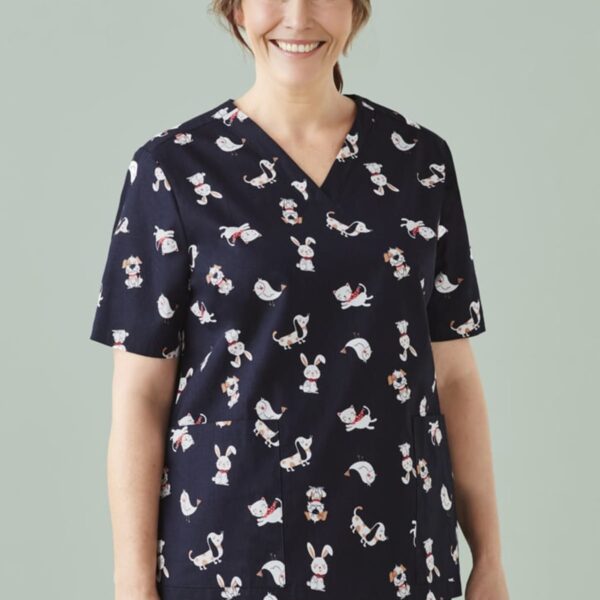 Smiling woman in animal-patterned scrubs against a light green background.