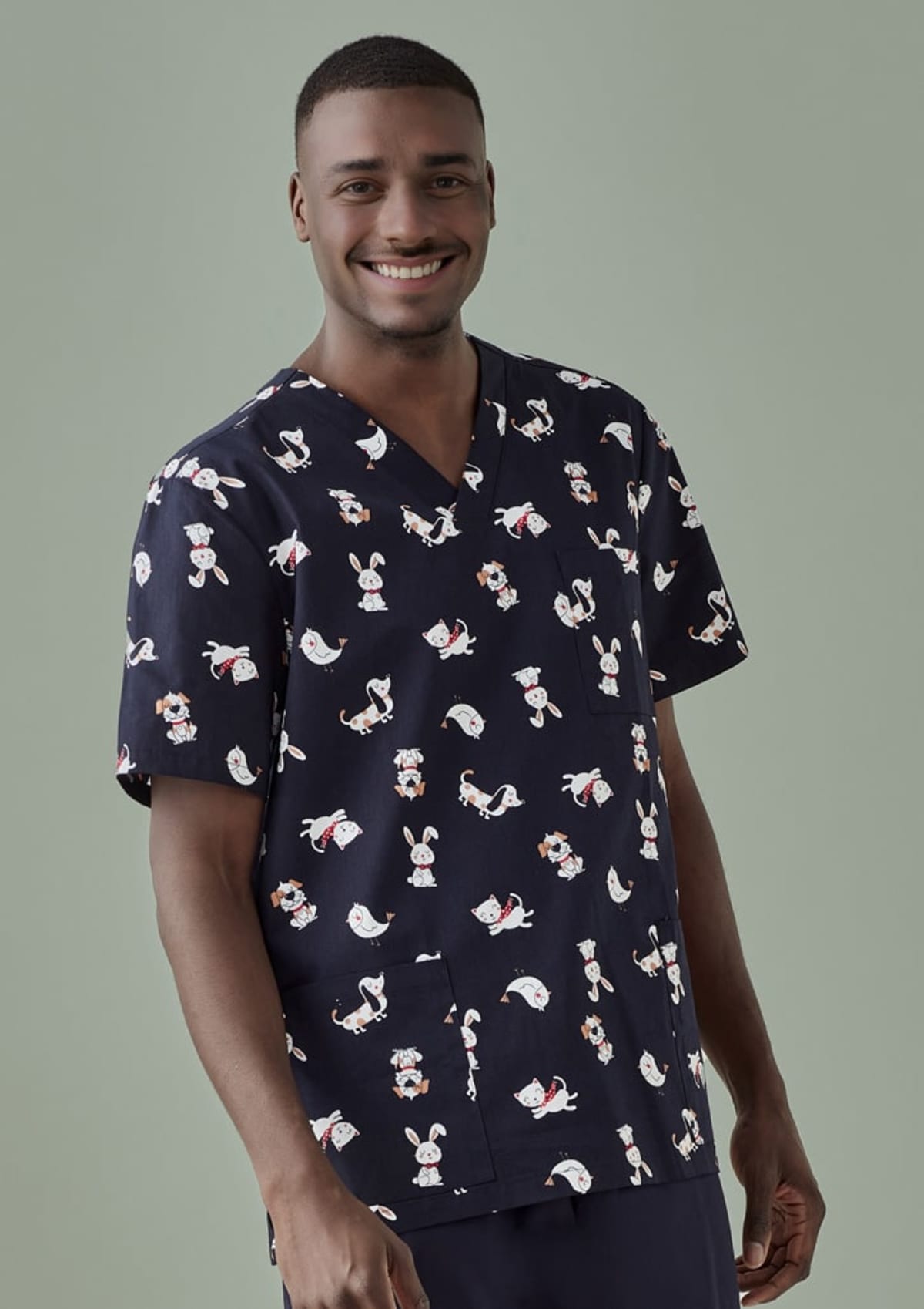 Man smiling, wearing a dark scrub top with animal patterns, against a plain background.