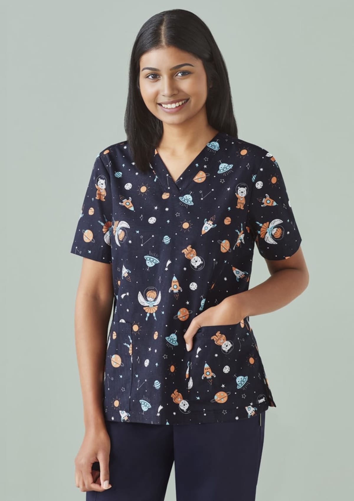 Person in a space-themed scrub top smiling against a light gray background.