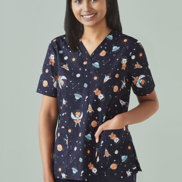 Person in dark scrubs with space-themed print, standing and smiling.