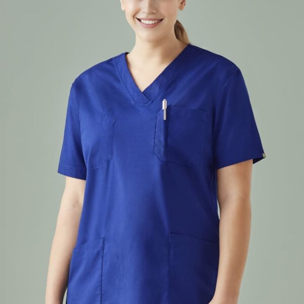 Person in blue medical scrubs smiling in front of a plain background.