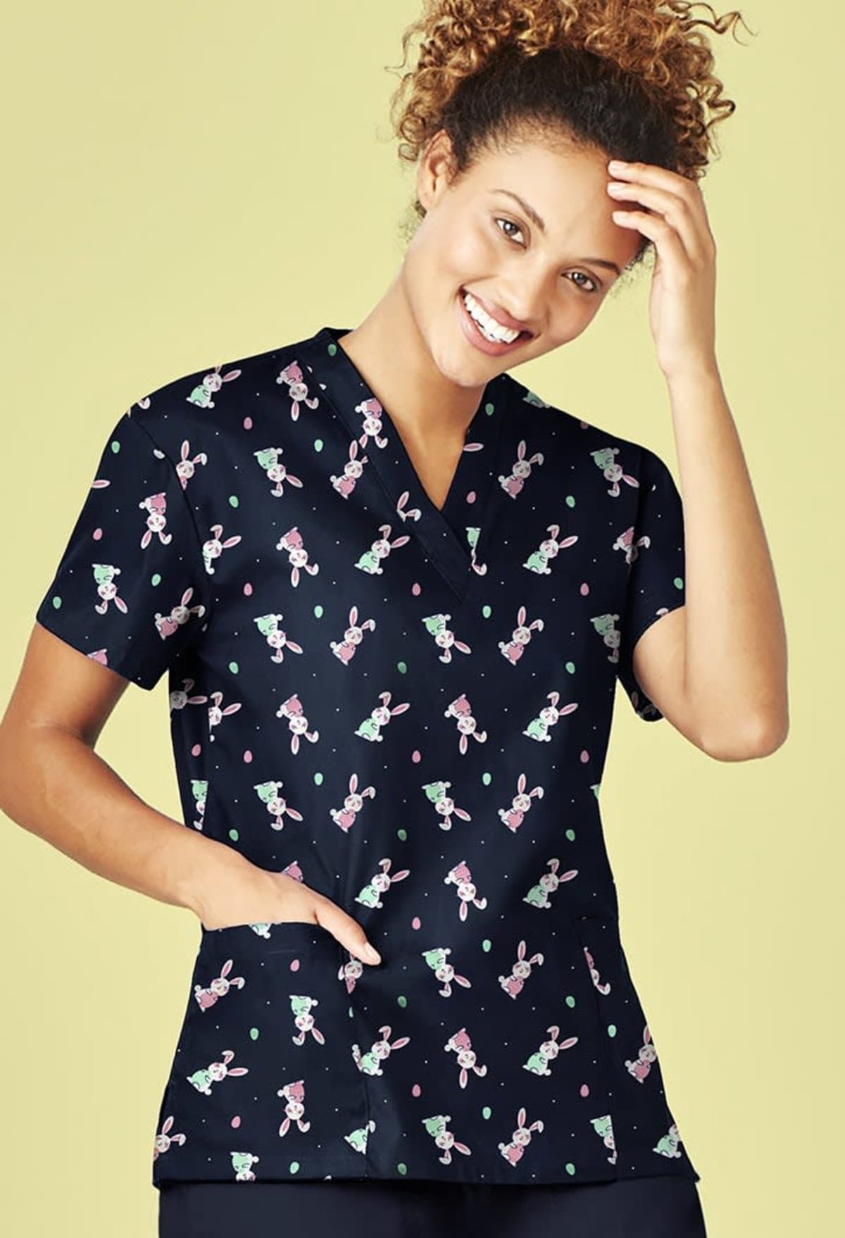 Person in bunny-patterned scrubs smiling against a light green background.