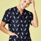 Person in a teddy bear patterned scrub top, smiling with one hand on head.