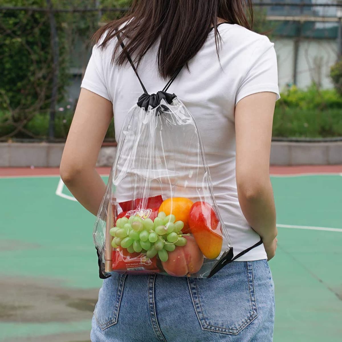 Person with a transparent backpack filled with fruits on a sports court.