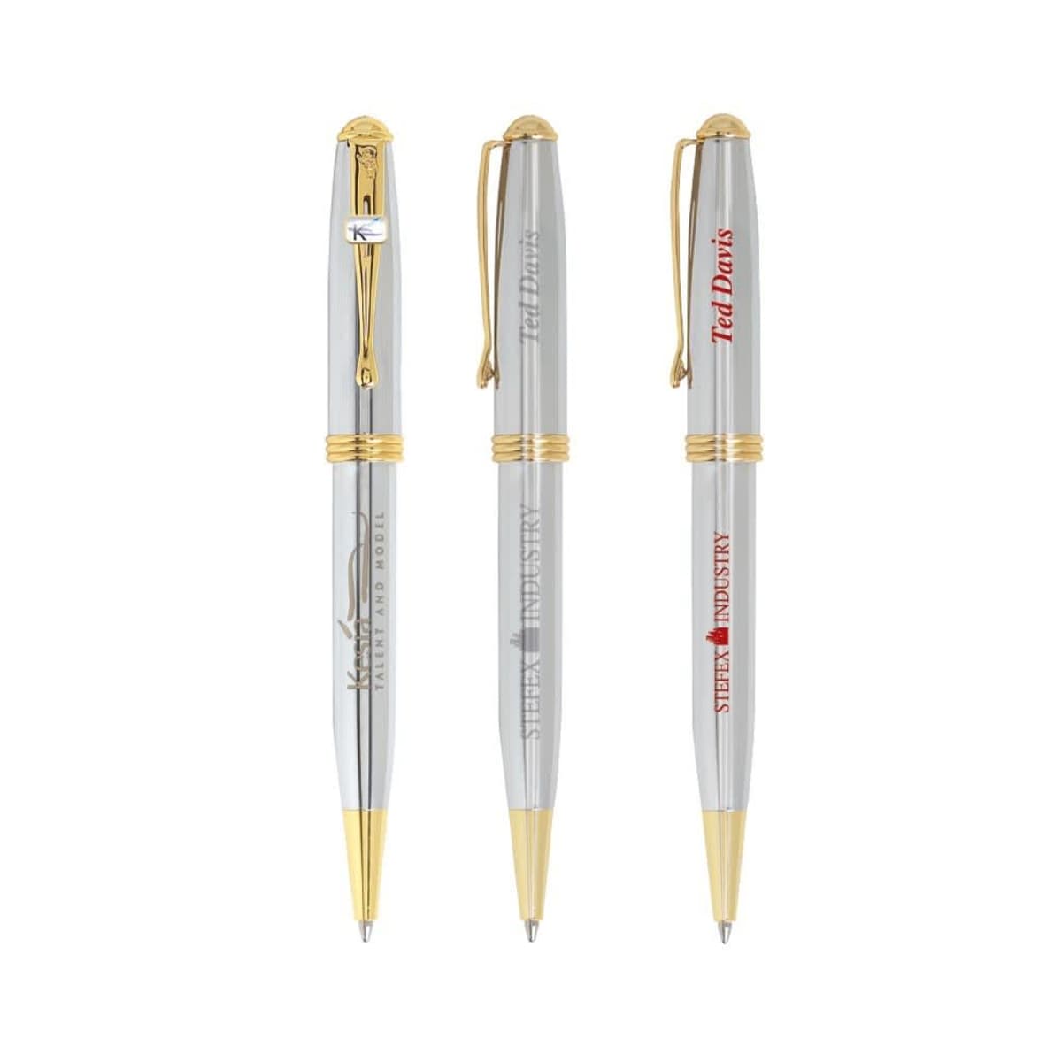 Three silver and gold ballpoint pens with different logos printed on their barrels.