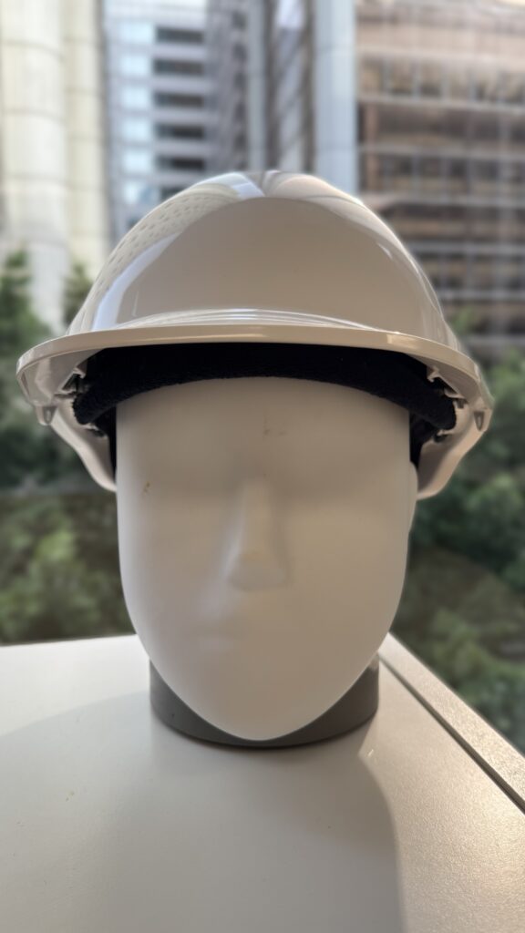 Mannequin head with a custom hard hat, cityscape view through the window behind.