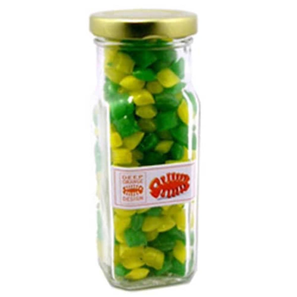 A glass jar filled with green and yellow candies, sealed with a gold lid.