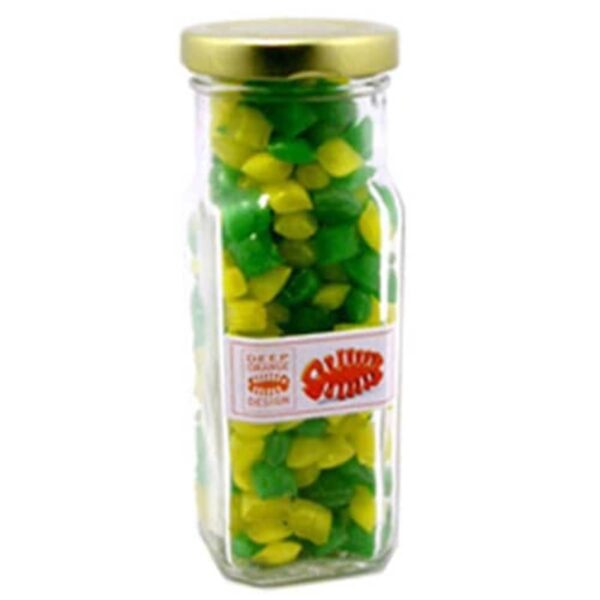 A glass jar filled with green and yellow candies, closed with a gold lid.