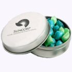 Round tin with Suncorp logo, filled with blue and green candies, lid partially open.