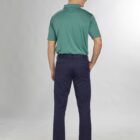 Man in green polo shirt and dark pants, standing, facing away against a light gray background.