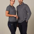 Two people wearing grey polo shirts and dark pants standing side by side.