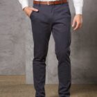 Person in white shirt and dark pants, hands in pockets, brown belt and shoes.