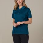 Person wearing a teal polo shirt and black shorts against a plain background.