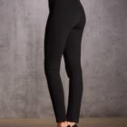 Person in black leggings and heels against a gray textured wall.