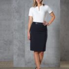Woman in a white blouse and black skirt standing against a gray background.