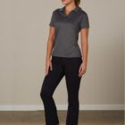 Person in gray polo shirt, black pants, and sneakers stands with hands by sides.