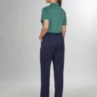 Person in green polo and blue pants, standing with hands in pockets, facing away.