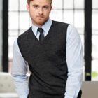 Man in gray vest and tie, sitting with a window background.