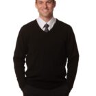 Man in a black sweater and tie smiling at the camera against a white background.