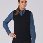 Person in blue shirt and black vest posing against a light background.