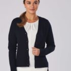 Woman in a navy cardigan over a white top, smiling with her hand near the buttons.