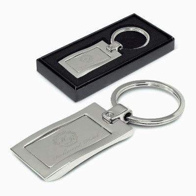 Rectangular silver metal key ring with engraved text, shown with a black gift box.