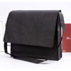 Black messenger bag with a flap over the top and a long shoulder strap.
