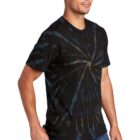 Man wearing a black and blue tie-dye T-shirt poses with his left hand in pocket.