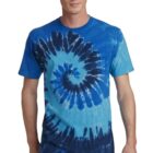 Person wearing a blue tie-dye t-shirt and jeans, standing and smiling.