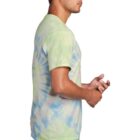 Man in a green and blue tie-dye shirt standing in profile.