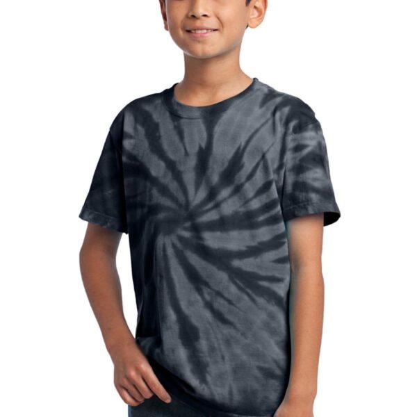 Boy in a black tie-dye shirt and jeans, smiling with hands in pockets.
