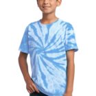 Boy wearing a blue tie-dye shirt and jeans, smiling with hands by waist.