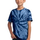Child wearing a blue tie-dye T-shirt and jeans, smiling with hands by side.