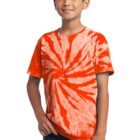 Boy in an orange tie-dye shirt with a spiral pattern, standing and smiling.