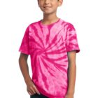 Boy in a pink tie-dye shirt and jeans, smiling with one hand in pocket.