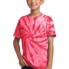 Boy in a red tie-dye shirt and jeans, smiling with hands in pockets.