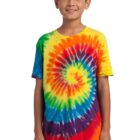 Child in a colorful tie-dye shirt smiles with hands by their sides.