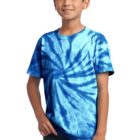 Smiling boy in a blue tie-dye shirt and jeans standing against a white background.