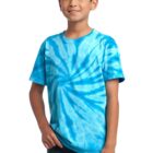 Boy in a blue tie-dye shirt and jeans, smiling with one hand in his pocket.
