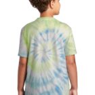 Child wearing a colorful tie-dye shirt and jeans, standing with back facing.